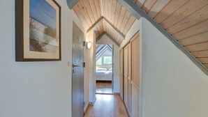 A narrow hallway with wooden flooring and a sloped ceiling. A bed is visible in the distance. - Child-friendly thatched cottage on a large plot. Natural property from private owner (Fereininsel Römö)