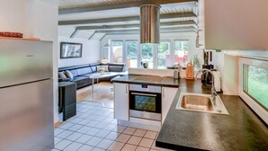 A modern kitchen with a built-in oven, a stainless steel sink, and a large window overlooking the garden. - Child-friendly thatched cottage on a large plot. Natural property from private owner (Fereininsel Römö)