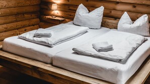 A wooden cabin bedroom with a skylight, a bed with pillows, and a bedside lamp. - Cozy round log villa with SwimSpa, whirlpool and sauna (Hellenthal)