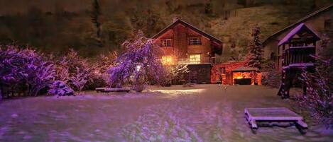 A rustic cabin with a wooden exterior, surrounded by snow-covered ground and trees.