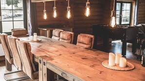 A wooden dining table with six chairs, candles, and hanging light fixtures in a rustic interior. - Cozy round log villa with SwimSpa, whirlpool and sauna (Hellenthal)