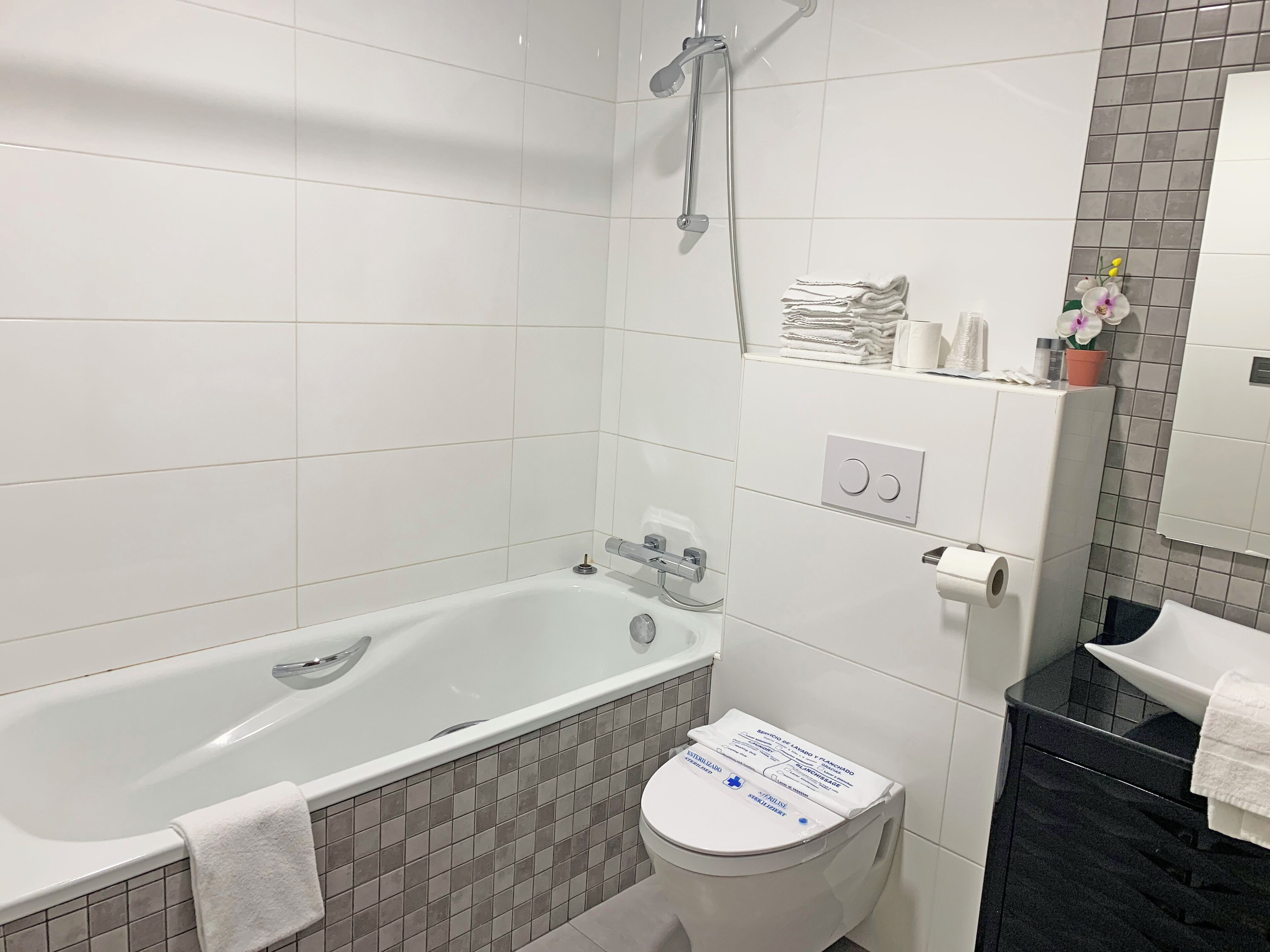 A bathroom with a bathtub, toilet, and a shower. There are towels and toiletries on the counter.