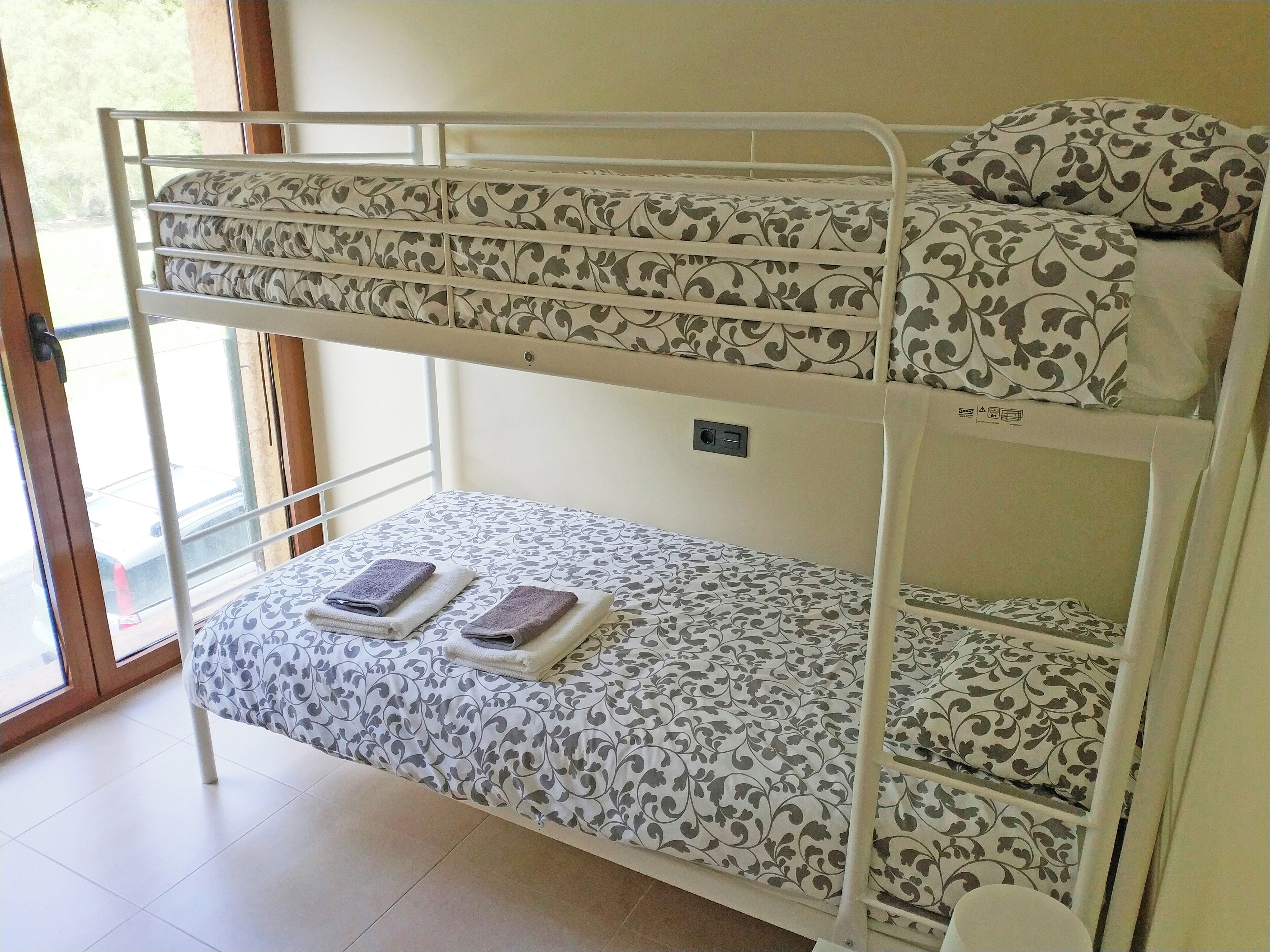A bunk bed with patterned bedding and a window view.