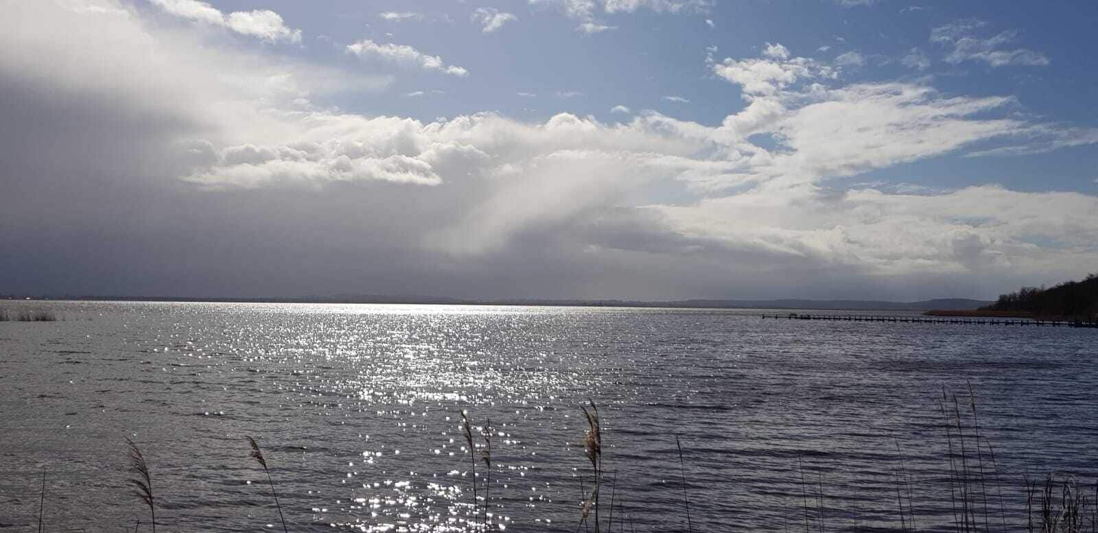 Un lac paisible, avec un ciel dégagé et une rive lointaine.