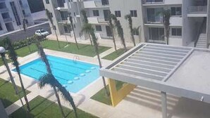 Un edificio moderno con piscina en la azotea y zona exterior cubierta.