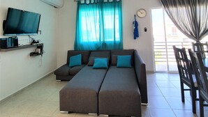 Una sala de estar con un conjunto de sofá, una televisión y un ventilador de techo.