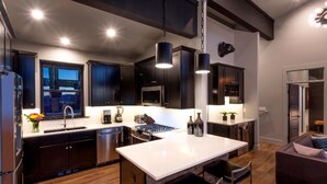 Une cuisine moderne avec des meubles de couleur sombre, des appareils en acier inoxydable et un îlot central.