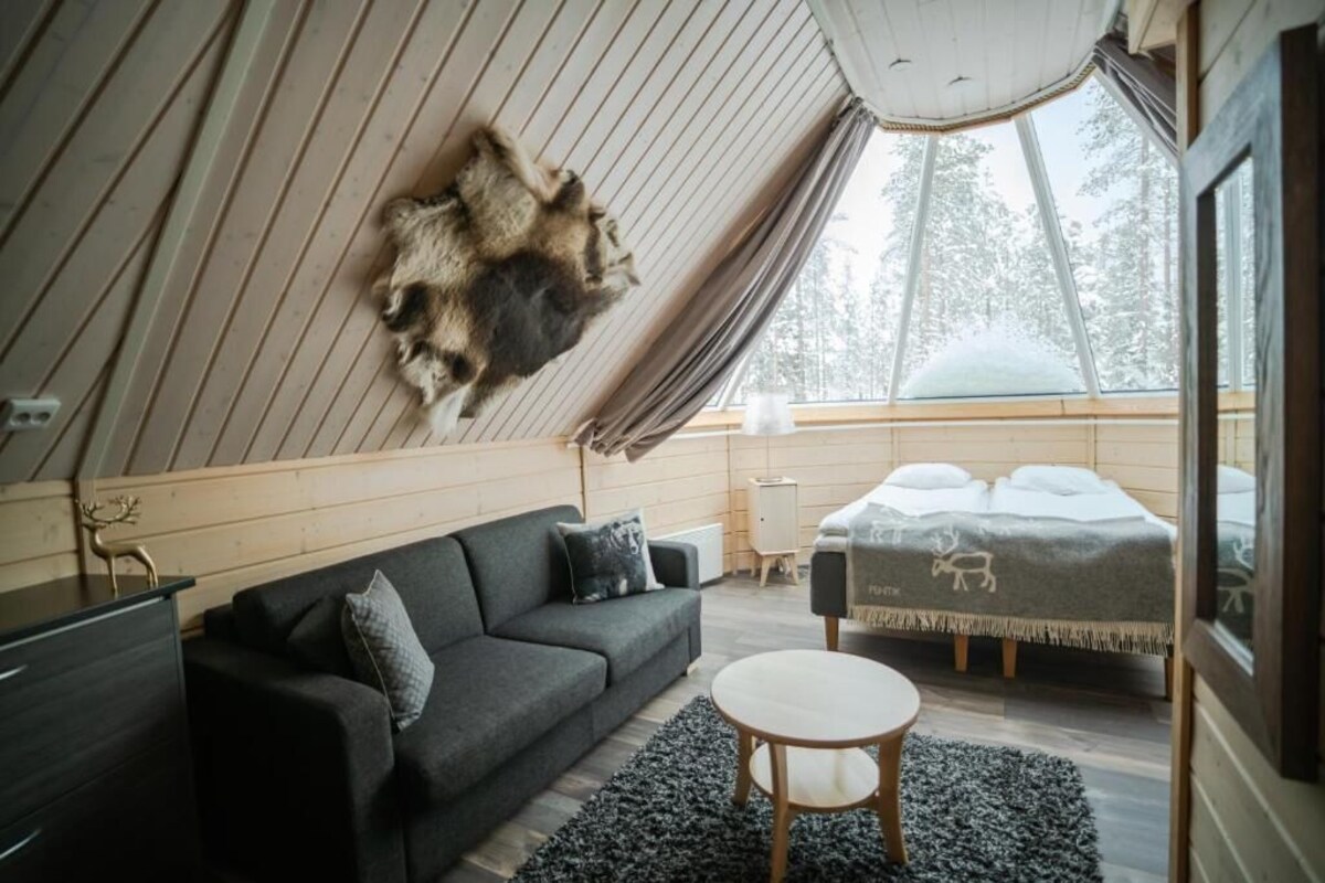 A cozy, modern interior with a large fur rug, a sofa, a round table, and a bed with a blanket featuring animal prints.