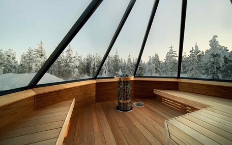 A modern interior with a wooden floor, a central fire pit, and a bench.