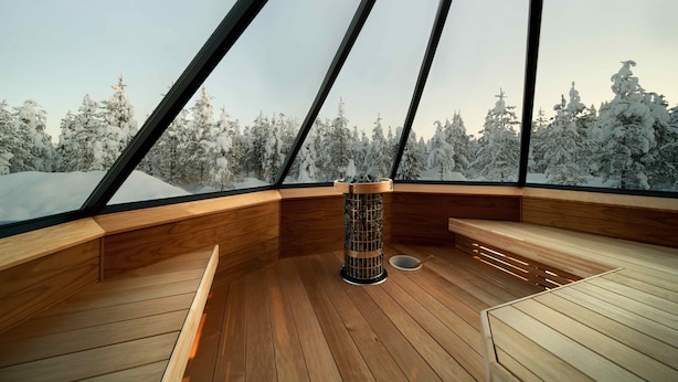 A modern interior with a wooden floor, a central fire pit, and a bench. - Northern Lights Village Levi (Kittila)