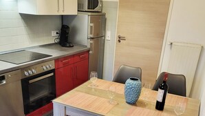 Een compacte keuken met moderne apparatuur, een eettafel met twee stoelen, en een deur naar een andere kamer.