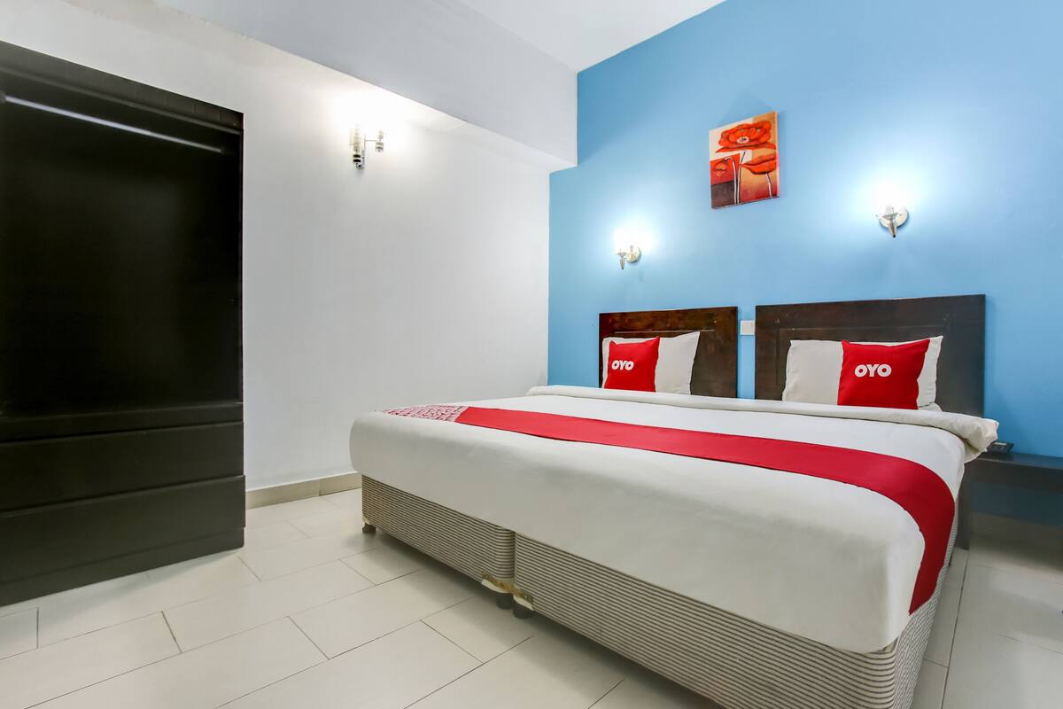 A hotel room with a bed, a TV, and a blue accent wall.