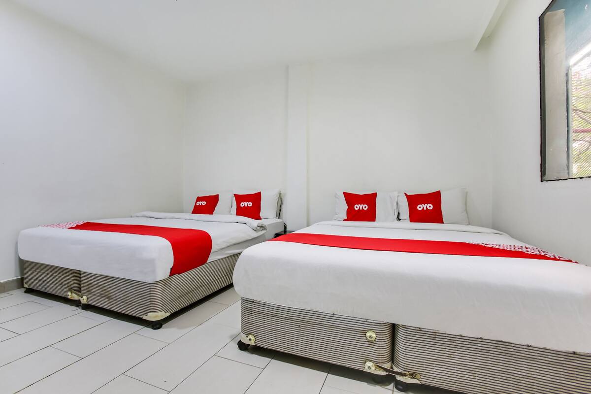 Two beds with red and white bedding, white walls, and a tiled floor.