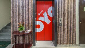 An elevator with a red interior and a logo, flanked by vertical wooden panels. - OYO 89571 Eco Palace Hotel (Kuala Lumpur)