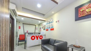 A reception area with a reception desk labeled "OYO," a black leather sofa, a small table with magazines, and a wall with clocks showing different time zones. - OYO 89571 Eco Palace Hotel (Kuala Lumpur)