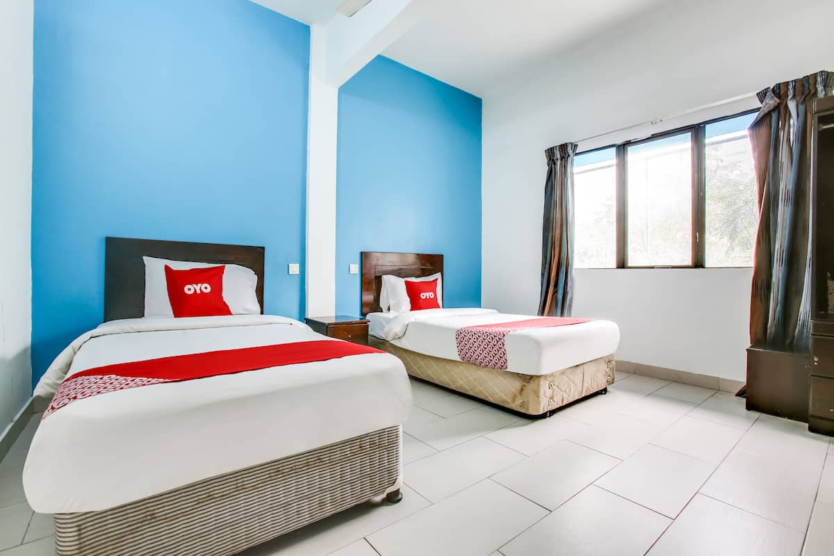 A hotel room with two beds, blue walls, a large window with curtains, and a white tiled floor.