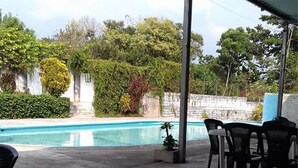 Un espacio al aire libre cubierto con una piscina, rodeado de vegetación y un muro de piedra.