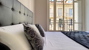 A bedroom with a large bed, a headboard, and a view of balconies through a window. - N&J - LILAS BUFFA - Central - Close sea (Niza)