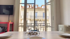 A dining table set with plates, cutlery, and wine glasses, with a view of a building through a window. - N&J - LILAS BUFFA - Central - Close sea (Niza)