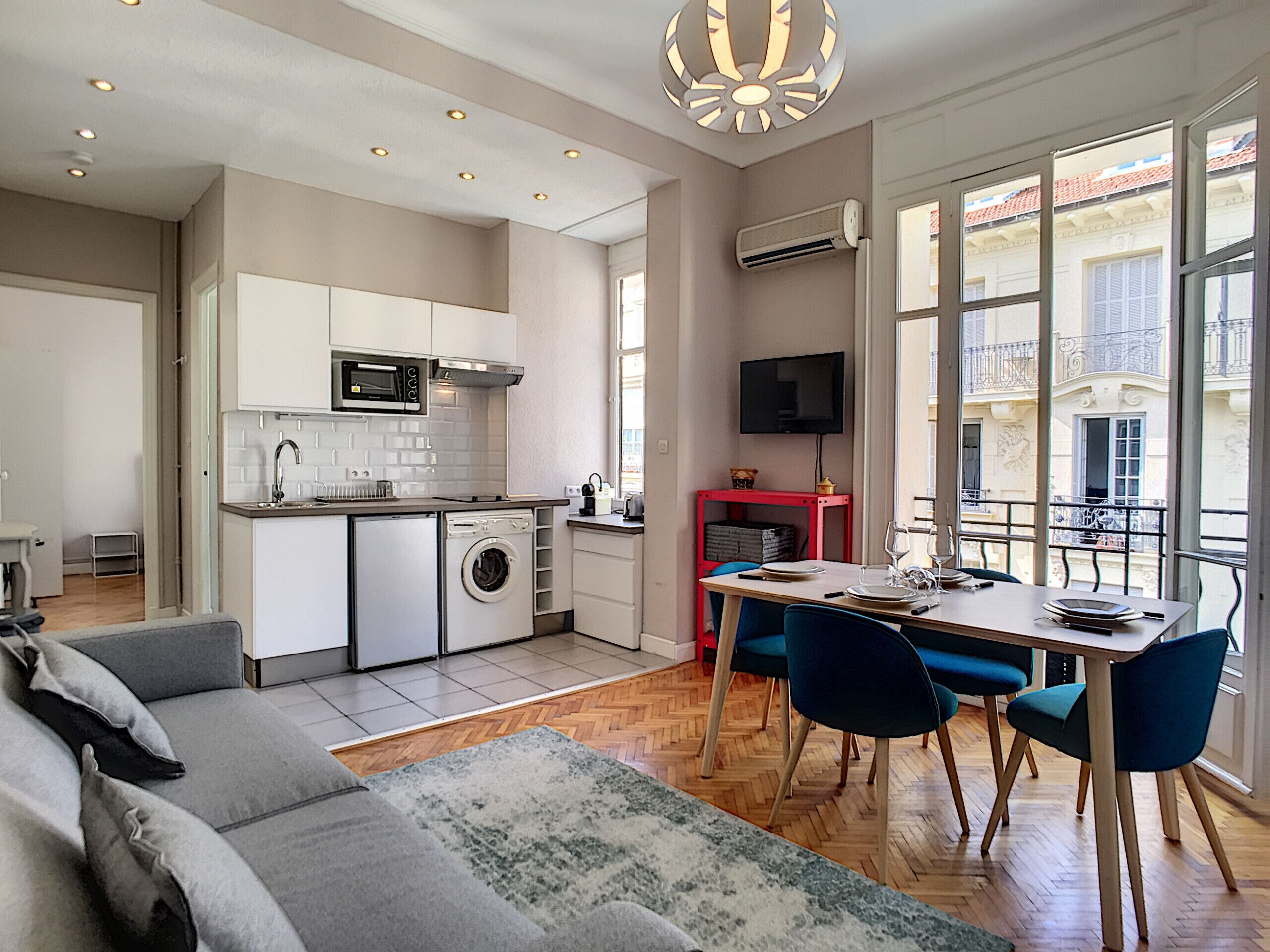 Eine moderne Küche mit Waschmaschine, Essbereich mit Stühlen und einer Couch.