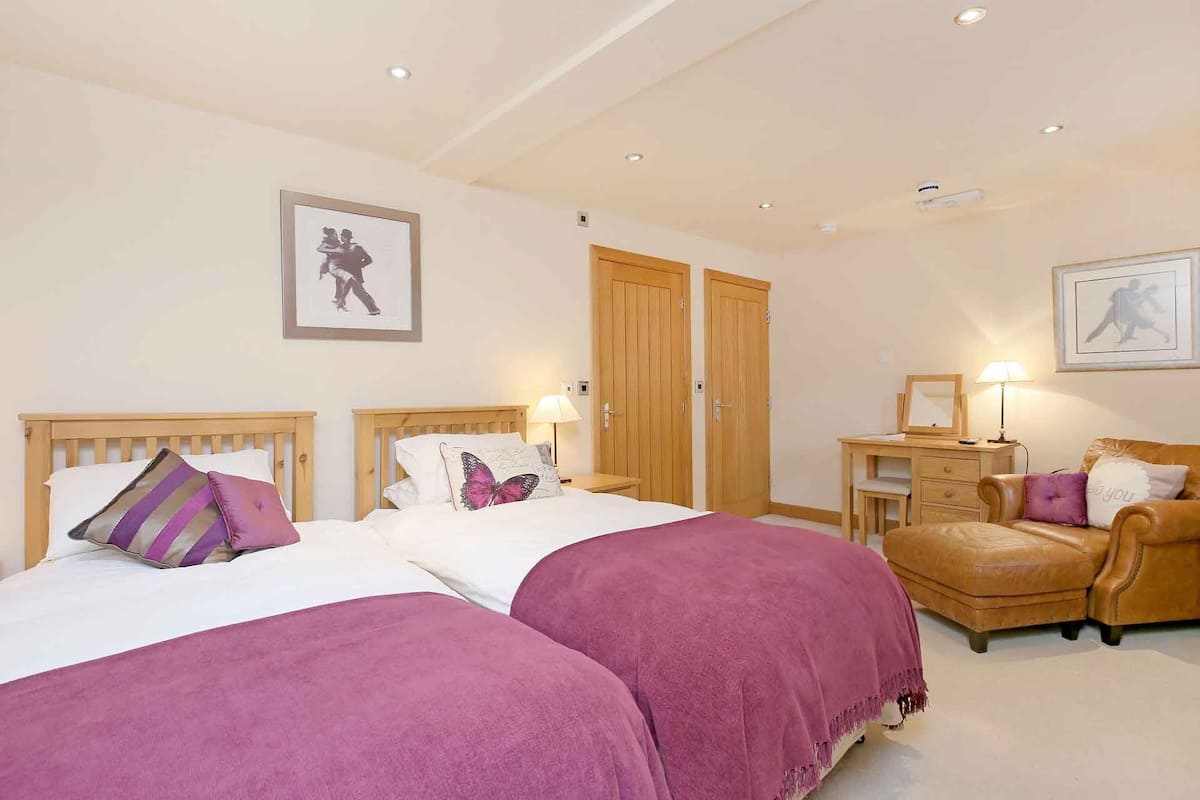 A bedroom with two beds, a desk, a chair, and two doors.