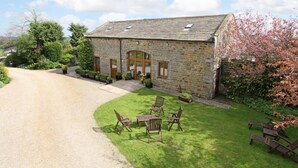 A stone building with a gravel driveway and a grassy lawn with outdoor furniture. - Cold Cotes Guest House (Harrogate)