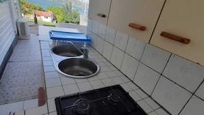 A kitchen with two sinks, a stove, and a view of the sea and mountains.