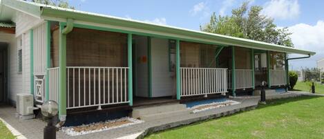 A motel with a covered porch, individual rooms, and a small outdoor area with a lawn.