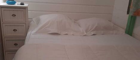 Ein Schlafzimmer mit einem Bett, einem Nachttisch und einer Lampe.