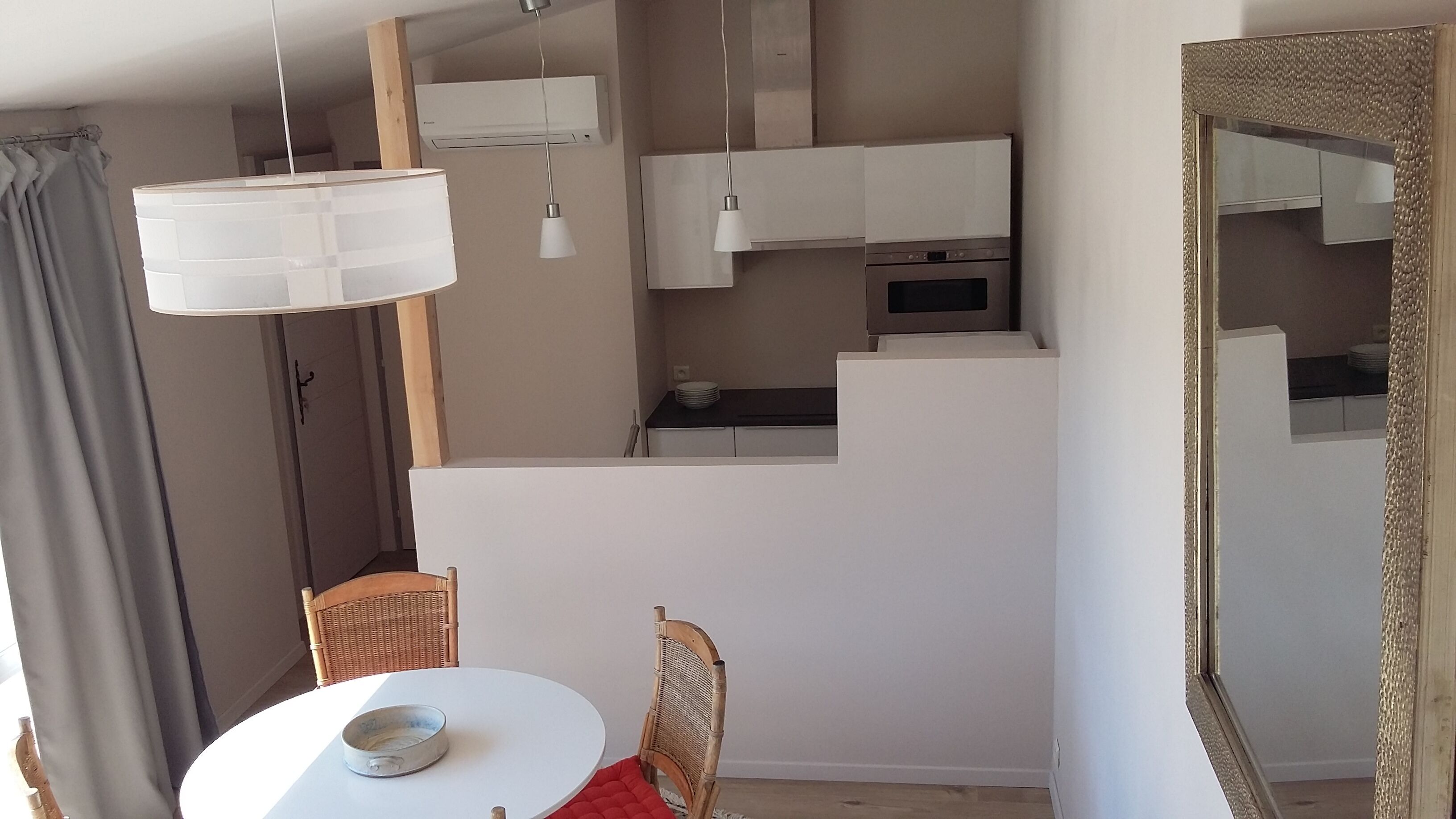 A compact living space with a dining area, kitchenette, and a large mirror.