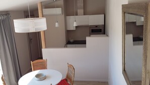 Een ruimtelijke leefruimte met een eethoek, kitchenette en een grote spiegel.