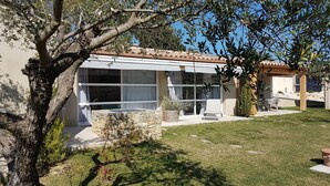 Een modern huis met een overdekte patio, een stenen muur en een gazon.