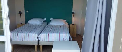 Een kamer met twee bedden, een klein tafeltje en twee bedlampen.