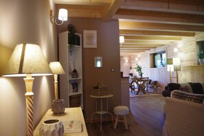 Un salon chaleureux avec un plancher en bois, un canapé, une table avec une lampe et un petit tabouret.