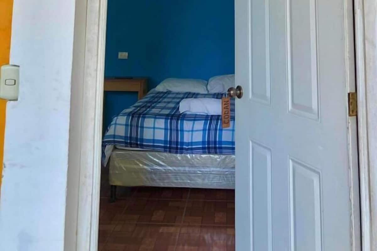 A room with a bed, a blue wall, and a door labeled "Coban".
