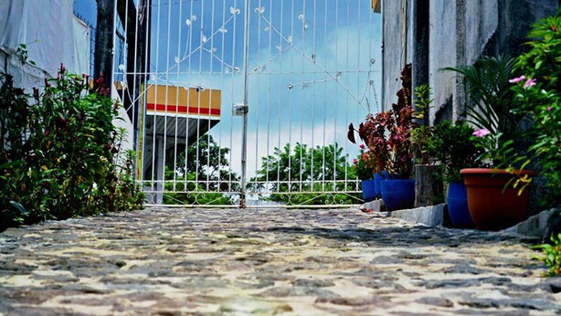 Una calle adoquinada que conduce a una entrada con puerta, con un edificio al fondo.