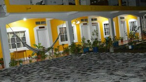 Un edificio con paredes amarillas y blancas, múltiples ventanas y plantas en macetas.