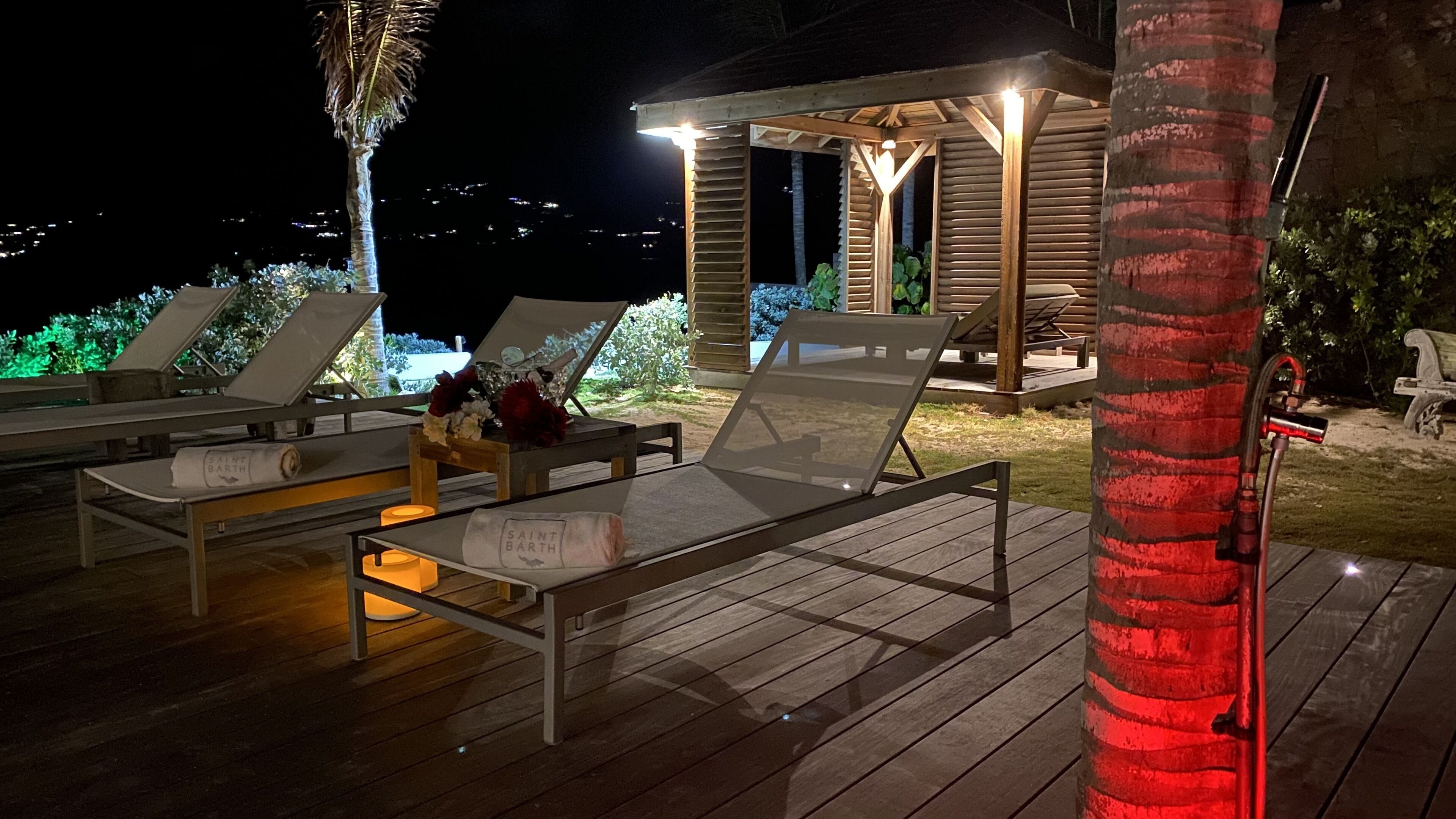 A wooden deck with lounge chairs and a small gazebo with a light.