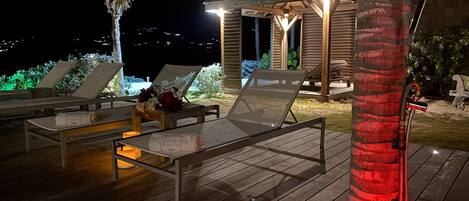A wooden deck with lounge chairs and a small gazebo with a light.