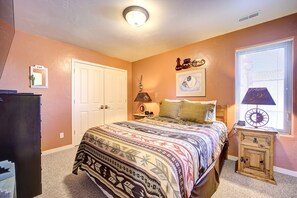 A bedroom with a bed, a nightstand, a dresser, and a window with blinds. - Awesome Retreat Pool ,Hot tub, 2 car garage (Moab)