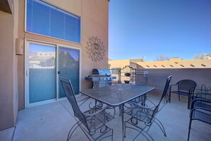 An outdoor patio with a metal table and chairs, a grill, and a sun-shaped wall decoration. - Awesome Retreat Pool ,Hot tub, 2 car garage (Moab)