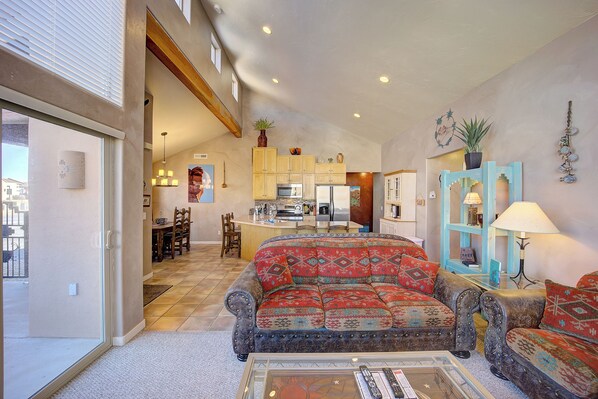 A spacious living area with a sofa, a coffee table, and a kitchen in the background. - Awesome Retreat Pool ,Hot tub, 2 car garage (Moab)
