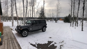 Een zwarte SUV geparkeerd op een besneeuwd houten terras.