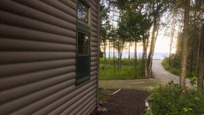 A cabin with a window and a dirt path leading to a forested area. - Lake Michigan Beach Home with Over 100’ of Private Sand Beach! Pets Welcome!  (Sturgeon Bay)