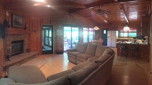 A cozy cabin interior with a fireplace, wooden walls, a sofa, and a dining area. - Lake Michigan Beach Home with Over 100’ of Private Sand Beach! Pets Welcome!  (Sturgeon Bay)