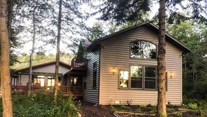 A cabin with a porch and a small deck, surrounded by dense forest. - Lake Michigan Beach Home with Over 100’ of Private Sand Beach! Pets Welcome!  (Sturgeon Bay)