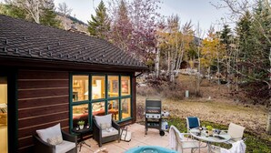 A wooden cabin with a hot tub, outdoor seating, and a barbecue area.