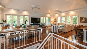 A spacious living area with a high ceiling, a dining area with a wooden table, and a seating area with a sofa and chairs.
