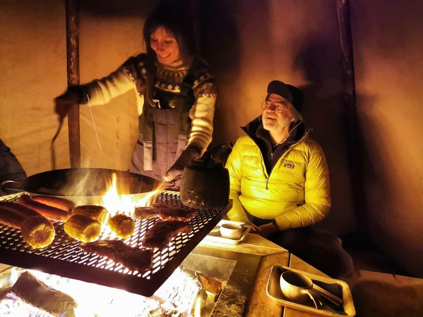 A person grilling sausages over an open fire.