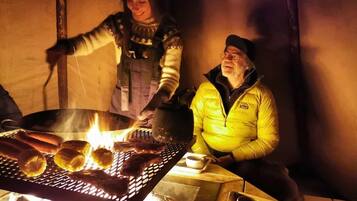 A person grilling sausages over an open fire.